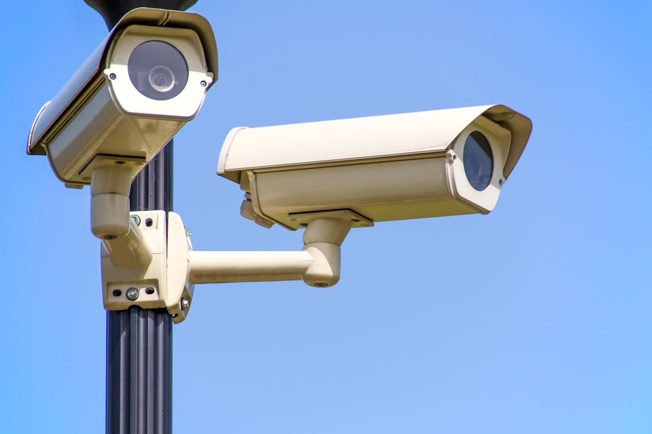 our-story-01 Outdoor security cameras mounted on a pole against a clear blue sky, ensuring vigilant surveillance.